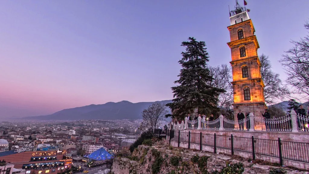 Bursa Tophane tarihi saat kulesi ve alacakaranlıkta şehir manzarası